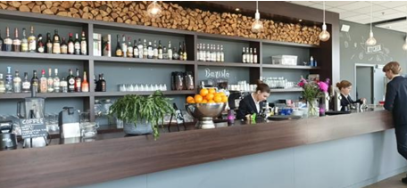 Cette photo montre l'espace d'un bar-restaurant d'application où les étudiants de la filière hôtellerie-restauration peuvent s'entraîner. Derrière le comptoir, on voit des étudiants en train de préparer des boissons. 